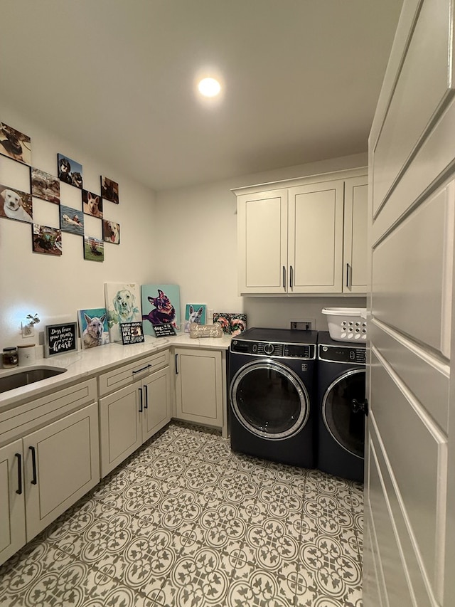 washroom with a sink, light tile patterned floors, washing machine and clothes dryer, and cabinet space