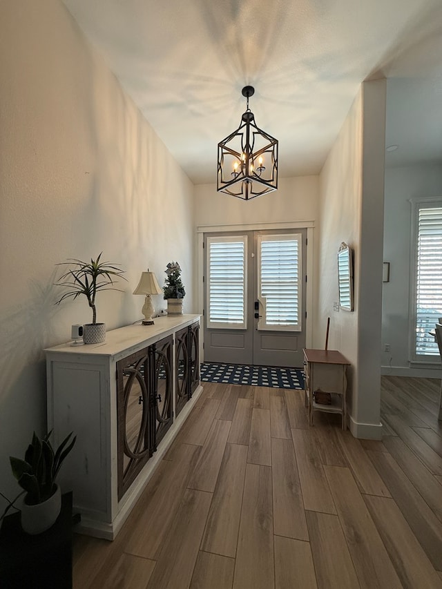 entryway featuring french doors, a notable chandelier, baseboards, and wood finished floors