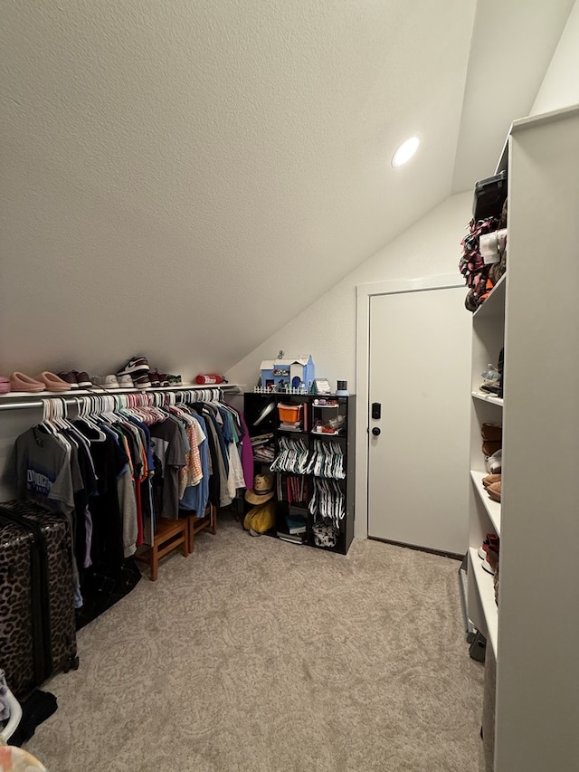 walk in closet with carpet and vaulted ceiling