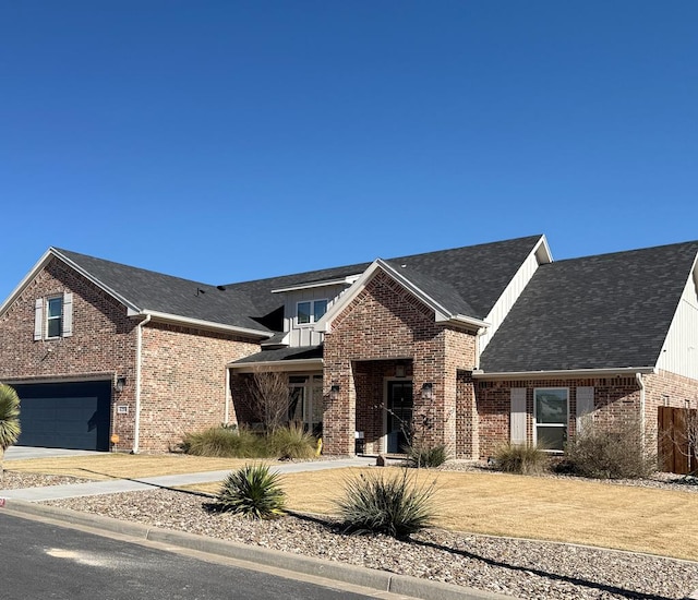 view of front of property featuring a shingled roof, a front yard, brick siding, and driveway