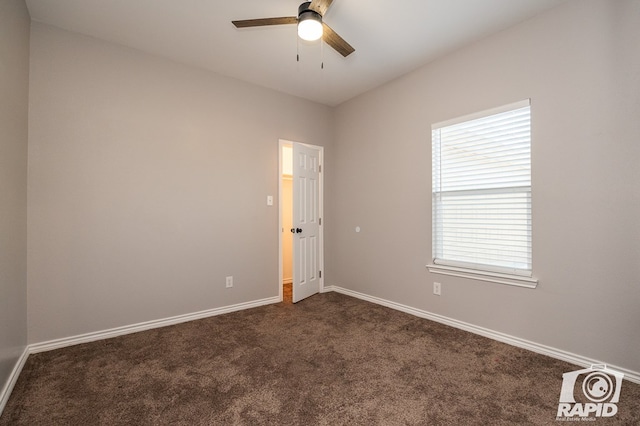 spare room featuring ceiling fan, plenty of natural light, and dark colored carpet