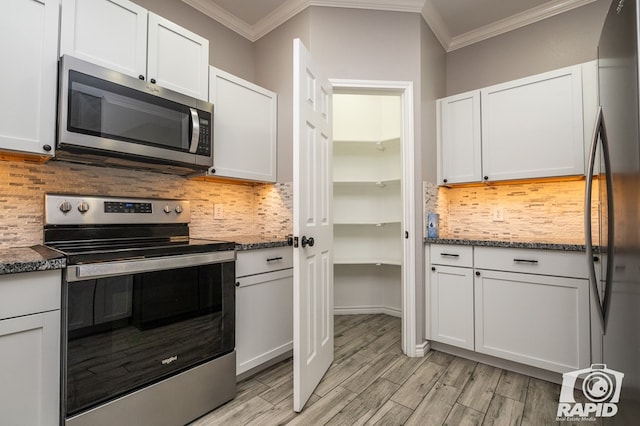 kitchen with decorative backsplash, white cabinets, and appliances with stainless steel finishes