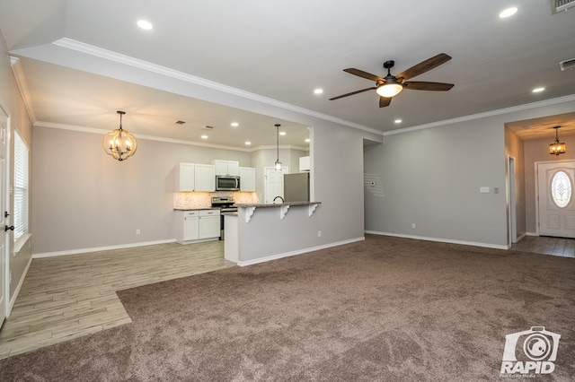 unfurnished living room featuring crown molding, ceiling fan with notable chandelier, and light carpet