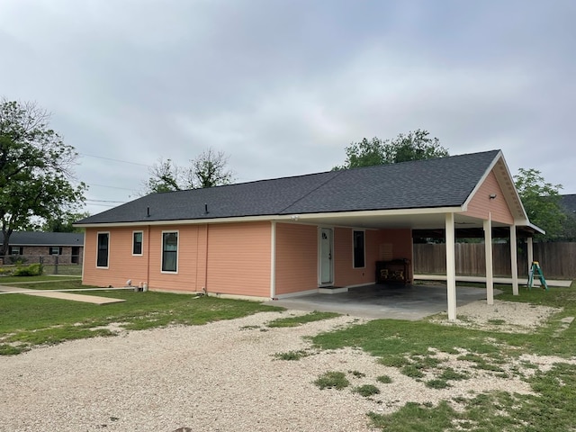 exterior space with fence, a shingled roof, driveway, and an attached carport