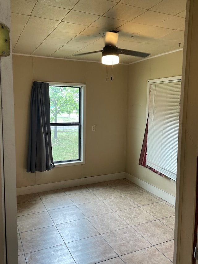 unfurnished room with baseboards, ceiling fan, and light tile patterned flooring