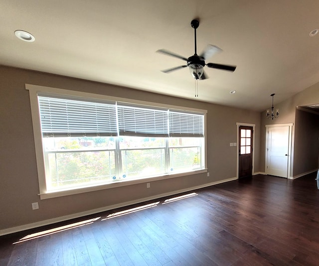 unfurnished living room with ceiling fan with notable chandelier, vaulted ceiling, and dark hardwood / wood-style floors