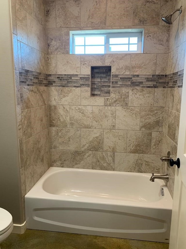 bathroom featuring tiled shower / bath and toilet