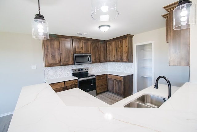 kitchen featuring decorative light fixtures, sink, decorative backsplash, light stone counters, and stainless steel appliances