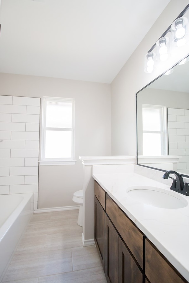 full bathroom with vanity, tiled shower / bath combo, a wealth of natural light, and toilet