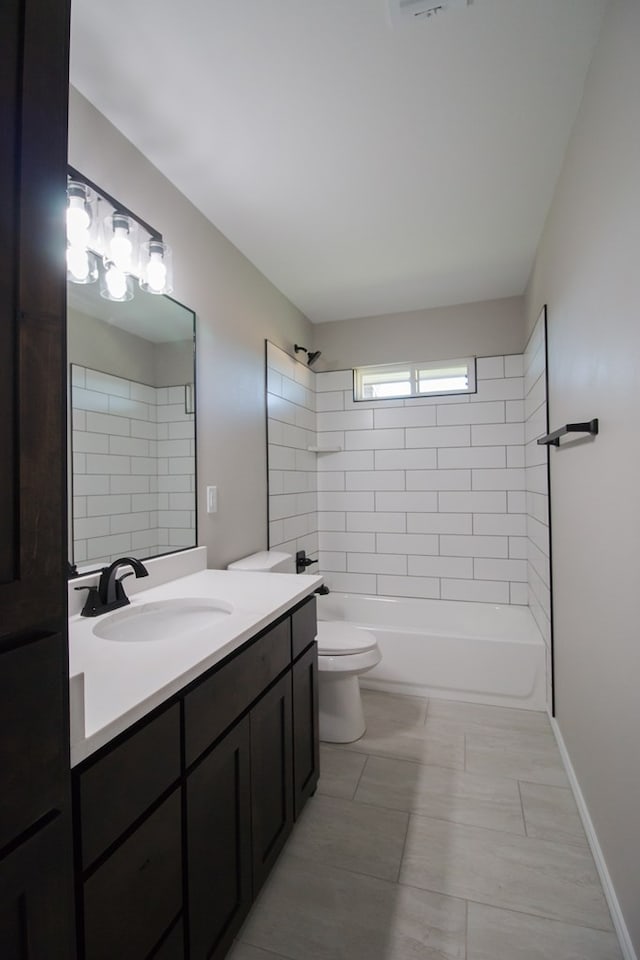 full bathroom featuring tiled shower / bath, vanity, tile patterned floors, and toilet