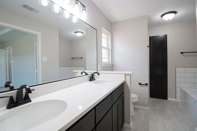 bathroom with vanity, a bath, and toilet