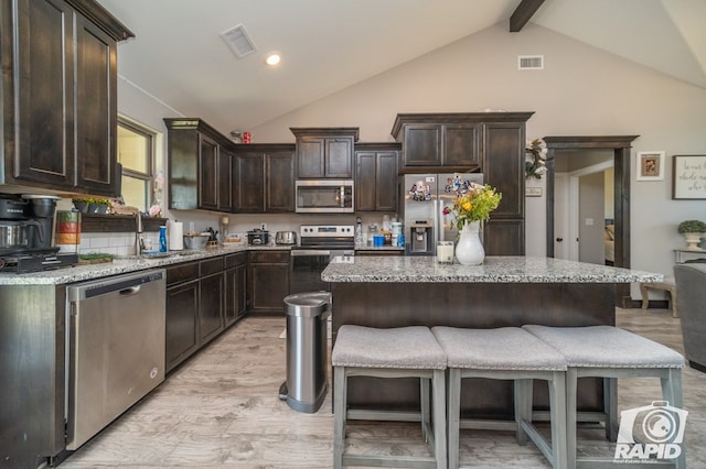 kitchen with visible vents, a kitchen breakfast bar, a center island, dark brown cabinetry, and appliances with stainless steel finishes