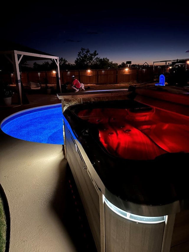 pool at night with a fenced backyard