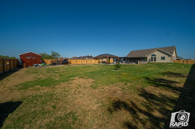 view of yard featuring a gazebo, a storage unit, an outdoor structure, and a fenced backyard