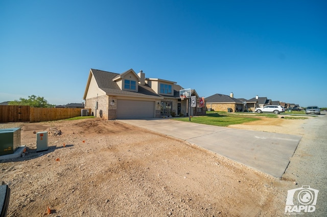 view of front facade with central AC unit, fence, driveway, an attached garage, and brick siding