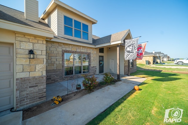 doorway to property featuring stone siding, a lawn, and roof with shingles