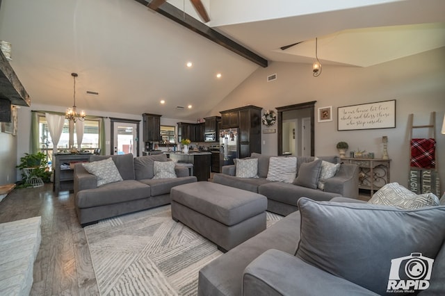 living area featuring visible vents, beam ceiling, wood finished floors, a notable chandelier, and high vaulted ceiling