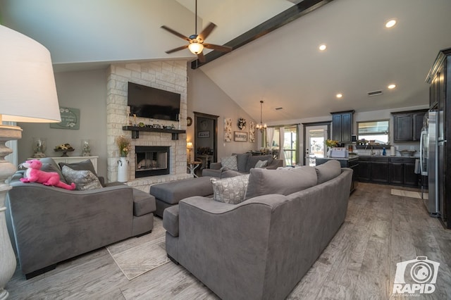 living room featuring visible vents, light wood finished floors, high vaulted ceiling, a fireplace, and ceiling fan