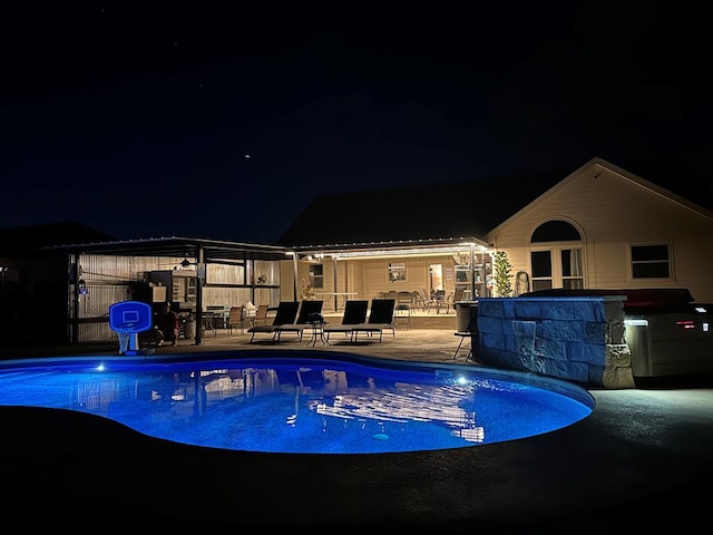 pool at night featuring a patio and a fenced in pool