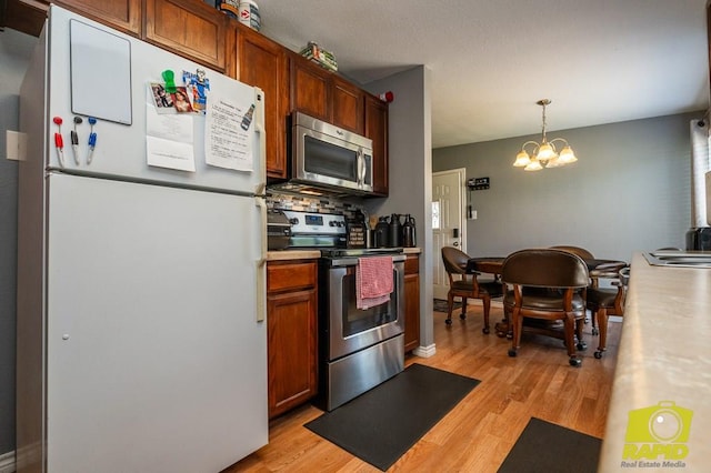 2123 Wilson St, San Angelo, TX 76901 - kitchen featuring stainless steel appliances, a chandelier, light wood finished floors, decorative light fixtures, and light countertops