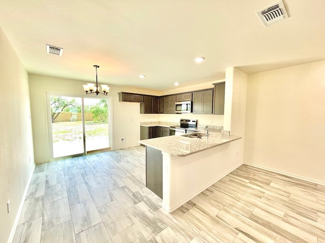 115 E 41st St, San Angelo, TX 76903 - kitchen featuring appliances with stainless steel finishes, a chandelier, a peninsula, light stone counters, and dark brown cabinetry