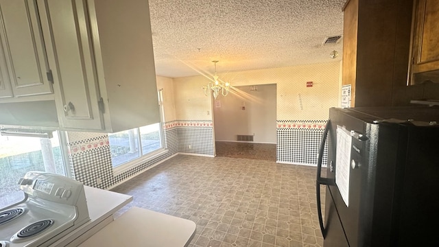 kitchen with fridge, a textured ceiling, and a chandelier