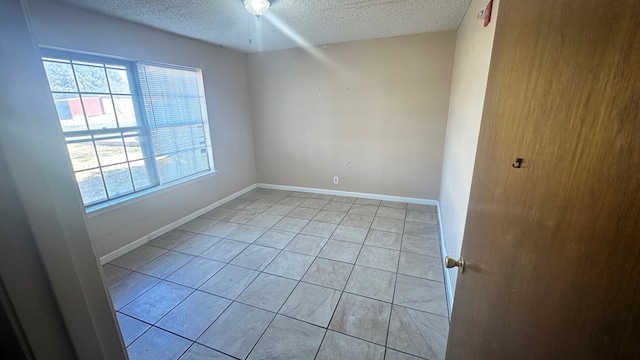 tiled empty room featuring plenty of natural light and a textured ceiling