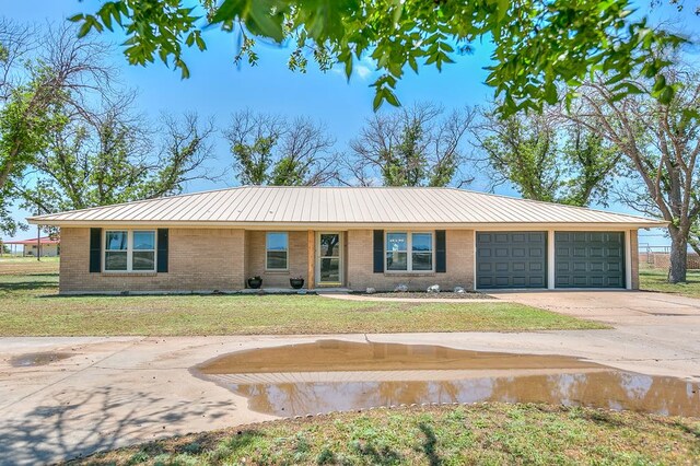 7077 Bean Rd, Wall, TX 76957 - ranch-style house with brick siding, concrete driveway, an attached garage, a front yard, and metal roof