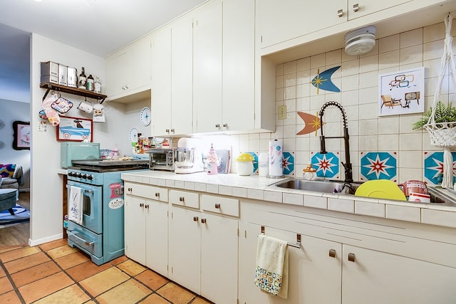 kitchen featuring white cabinetry, tile counters, stainless steel gas range, and decorative backsplash