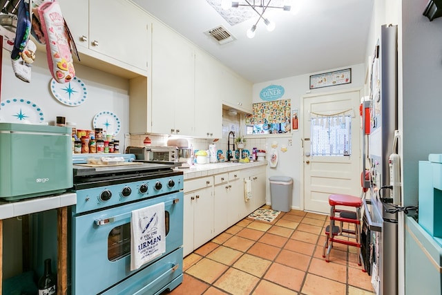 kitchen featuring stove, light tile patterned floors, and white cabinets