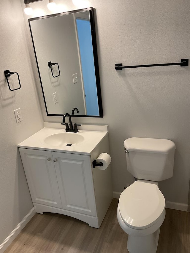 709 E Harris Ave, San Angelo, TX 76903 - half bath featuring wood finished floors, vanity, toilet, and baseboards