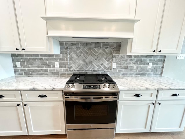 kitchen featuring light stone countertops, gas stove, and white cabinets