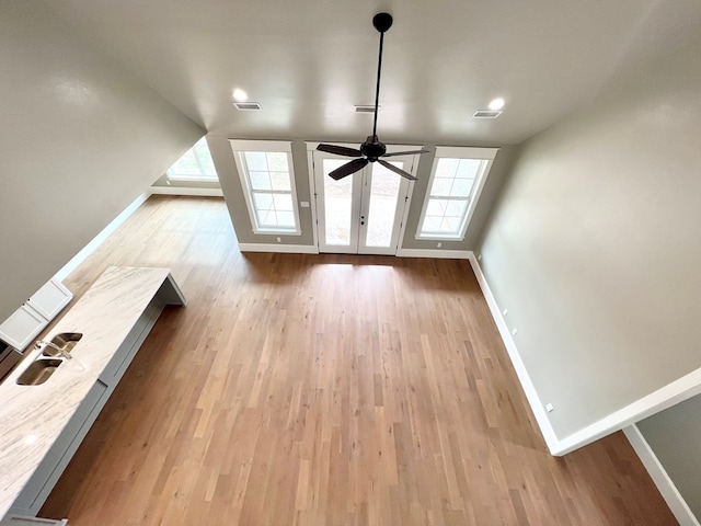 unfurnished living room with lofted ceiling, ceiling fan, light hardwood / wood-style flooring, and a healthy amount of sunlight