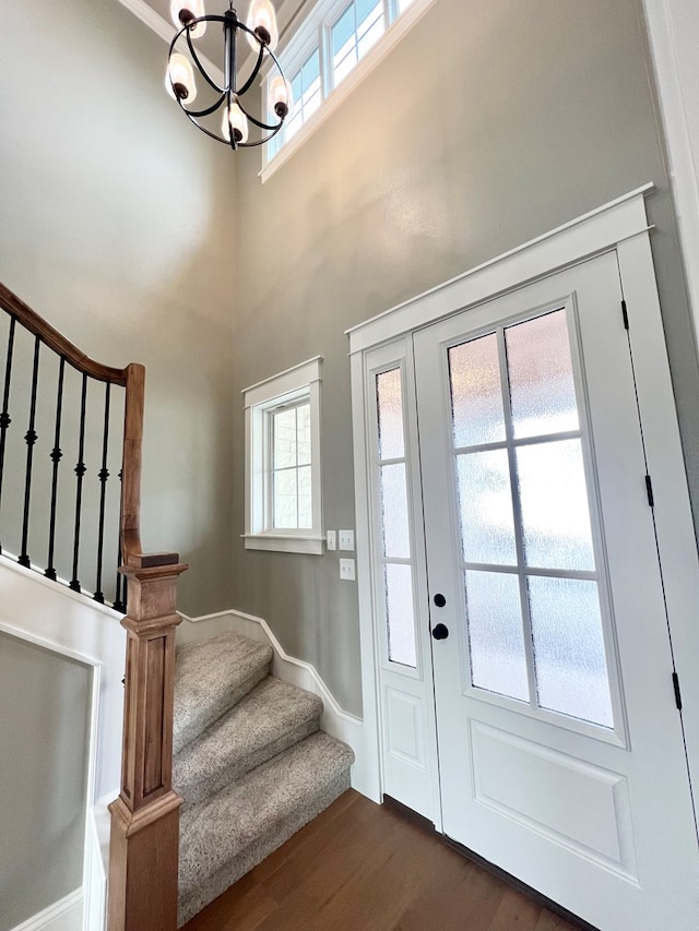 doorway featuring an inviting chandelier, dark wood-type flooring, and a high ceiling