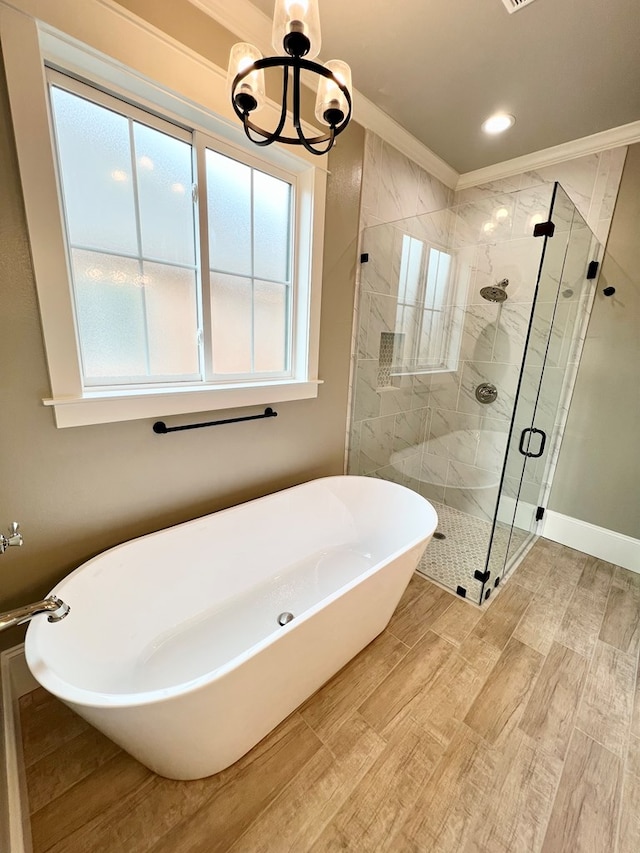 bathroom with hardwood / wood-style flooring, ornamental molding, separate shower and tub, and a notable chandelier