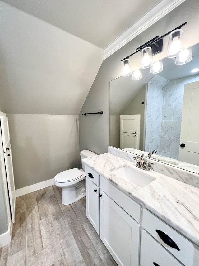 bathroom featuring vanity, hardwood / wood-style flooring, vaulted ceiling, and toilet