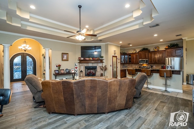 living room featuring french doors, a tray ceiling, hardwood / wood-style floors, ceiling fan, and decorative columns