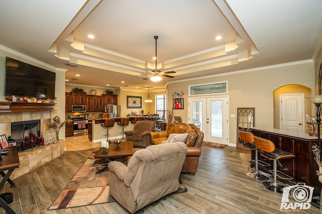 living room with french doors, light wood-type flooring, and a tray ceiling