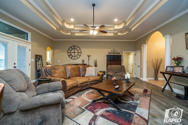 living room featuring ornamental molding, wood-type flooring, a raised ceiling, and ornate columns