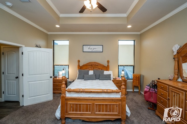 bedroom with a raised ceiling, crown molding, and dark carpet