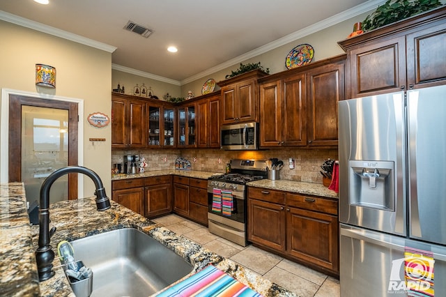 kitchen with appliances with stainless steel finishes, sink, decorative backsplash, ornamental molding, and light stone counters