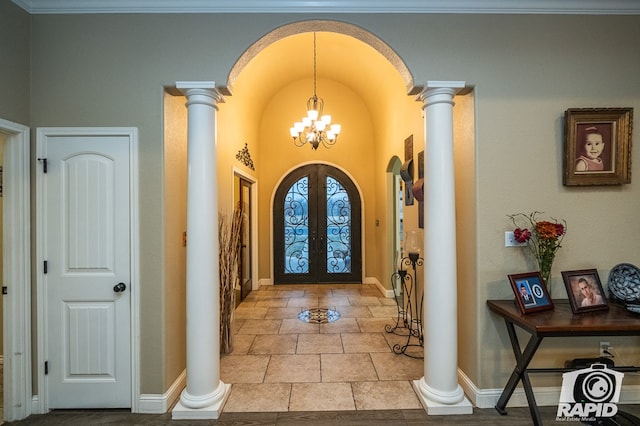 entrance foyer featuring decorative columns, an inviting chandelier, and french doors