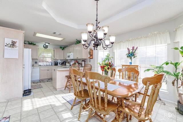 dining space with a tray ceiling, visible vents, and a notable chandelier