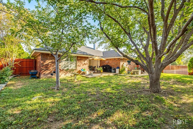 back of property with a yard, a patio area, and brick siding