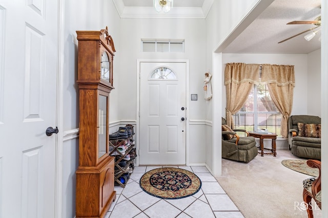 carpeted entrance foyer with ceiling fan and ornamental molding