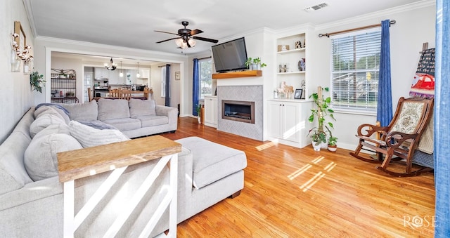 1601 S Jackson St, San Angelo, TX 76903 - living area with ornamental molding, light wood-style floors, a ceiling fan, a tiled fireplace, and a chandelier