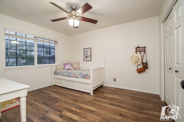 bedroom with dark wood-type flooring, a closet, baseboards, and a ceiling fan