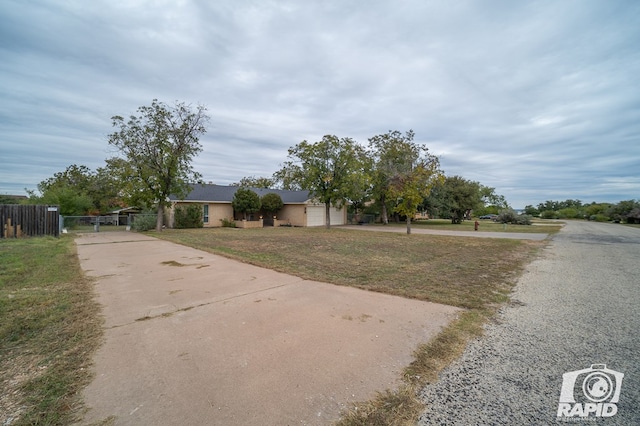 view of front of home with concrete driveway, fence, a front lawn, and a gate