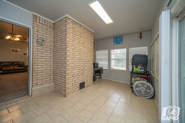 interior space featuring tile patterned floors, brick wall, and ceiling fan