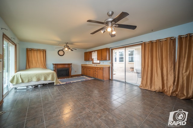 unfurnished bedroom featuring a ceiling fan, access to exterior, a fireplace, and multiple windows